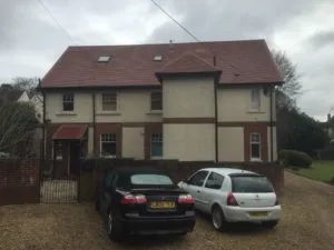 Two cars parked in front of a house.